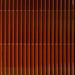 Raking light over the dense ceramic rib of a Rombini wall