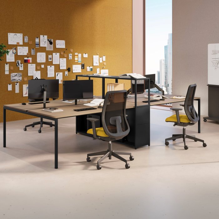 Italian bench desking with fabric screens and shared cable raceways on a corporate workstation floor in Bengaluru